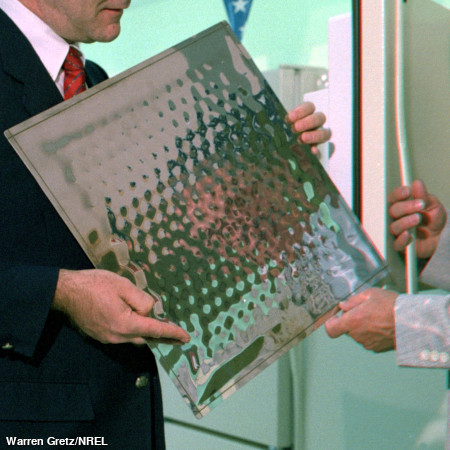 A man holding a small, compact vacuum insulation (CVI) panel from a refrigerator.