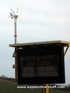 turbina wiatrowa i panel słoneczny zasilające znak budowy drogi.