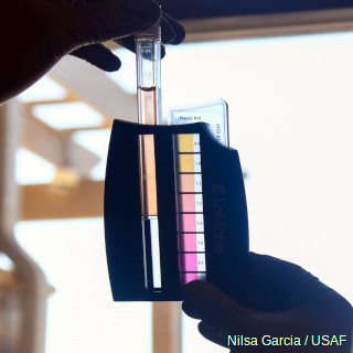 Testing the pH of a water sample by comparing against a colored pH scale.