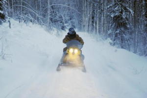 Photo of a snowmobile racing down a snowbound road in Alaska.