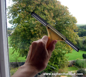 Cleaning a window by hand with a squeegee.